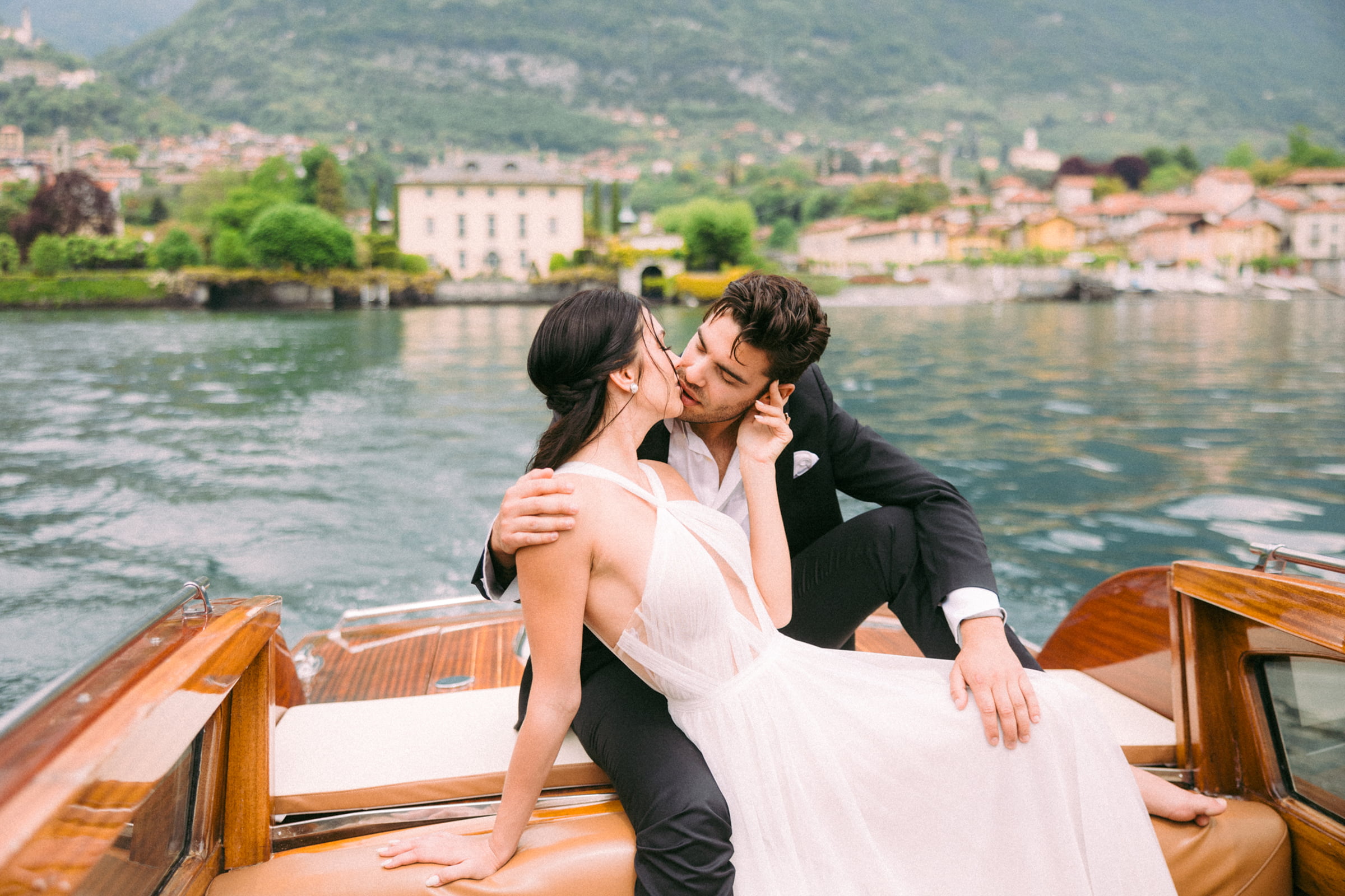 A couple sharing a kiss on a wooden boat on a mountain lake